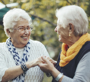 Porträt von zwei Seniorinnen, die sich an den Händen halten