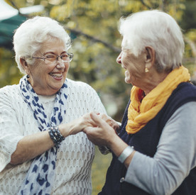 Porträt von zwei Seniorinnen, die sich an den Händen halten