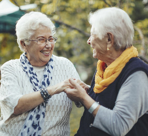 Porträt von zwei Seniorinnen, die sich an den Händen halten