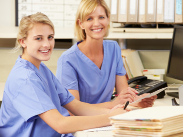 Auszubildende der Gesundheitsfachberufe mit Anleiterin an einem PC