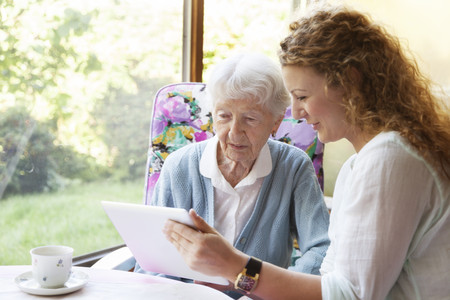 Seniorin mit junger Frau am Tablet