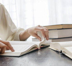 Zwei Personen sitzen mit Büchern an einem Tisch und lesen.