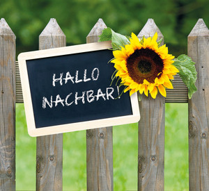 Schild an Gartenzaun mit der Aufschrift Hallo Nachbar!