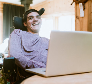 Ein Mann im Rollstuhl arbeitet am Laptop