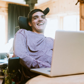 Ein Mann im Rollstuhl arbeitet am Laptop
