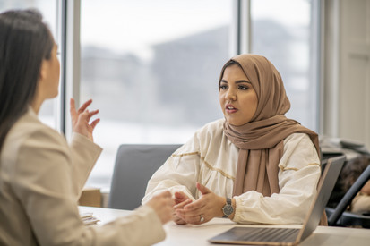 Zwei Frauen im Gespräch, eine von ihnen trägt einen Hijab