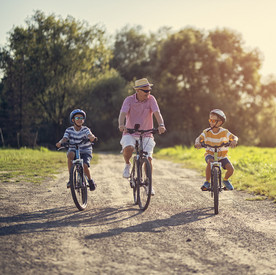 Großvater mit Enkeln, die am späten Nachmittag Fahrrad fahren.