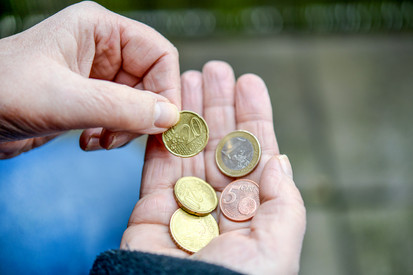 Eine ältere Person hält ein paar Euro- und Cent-Münzen in ihrer Hand. 