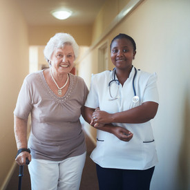 Pflegerin hilft Seniorin beim Laufen