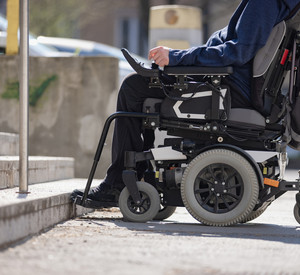 Eine Person im elektronischen Rollstuhl steht vor einer Treppe.