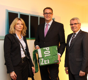 Polizeipräsident Karl-Heinz Weber und Heike Rowohlt übergeben eine Polizeitasche an Sozialminister Alexander Schweitzer
